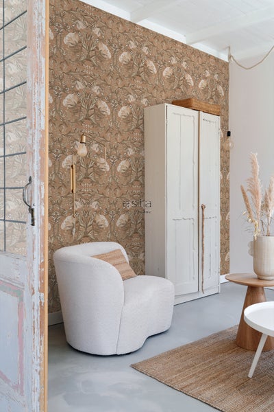 Wohnzimmer mit floral gemusterter Tapete, Sessel und Schrank