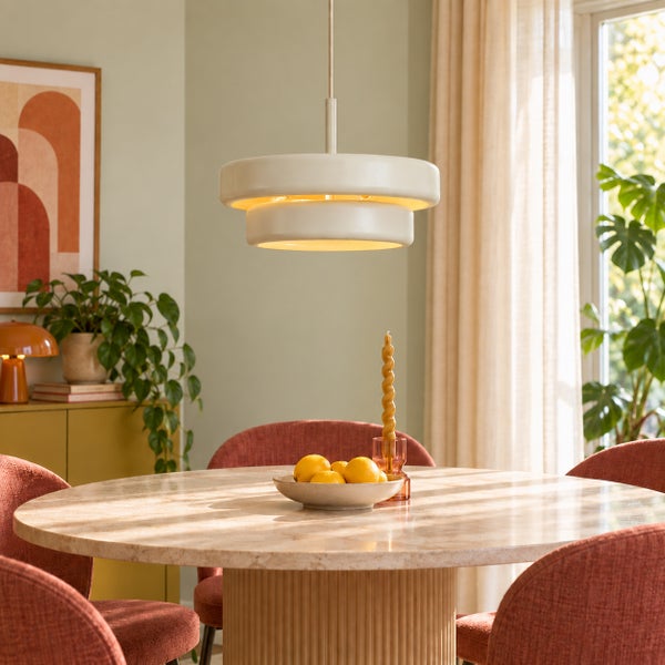 Moderne Hängelampe über einem runden Esstisch mit Marmorplatte und Stühlen in einem Wohnraum mit Pflanzen und dekorativen Accessoires.