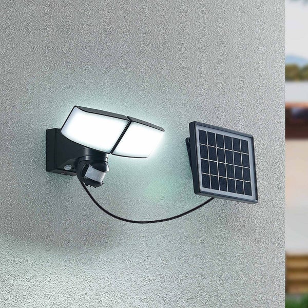 Solar-LED-Außenstrahler mit zwei verstellbaren Köpfen, Bewegungsmelder und separatem Solarpanel, an einer Wand montiert.