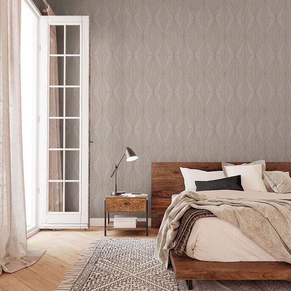Schlafzimmer mit geometrisch gemusterter Tapete, Holzbett, Nachttisch mit Lampe und Balkontür vor einem hellen, wohnlichen Ambiente.