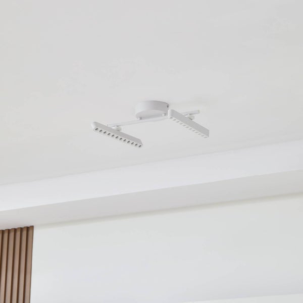 Moderne LED-Deckenleuchte in Weiß mit zwei verstellbaren, länglichen Strahlern auf einer runden Basis an einer hellen Decke montiert.