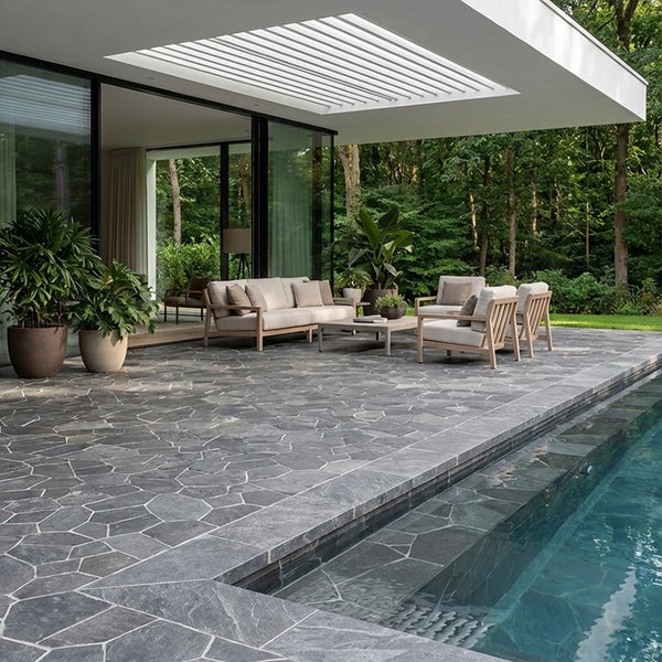 Moderne Terrasse mit Natursteinpflasterung am Pool und Gartenmöbeln aus Holz unter einer Pergola vor einem Wohnhaus.