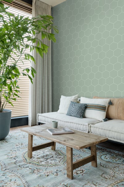 Wohnzimmer mit Sofa, Holztisch und geometrischer Tapete