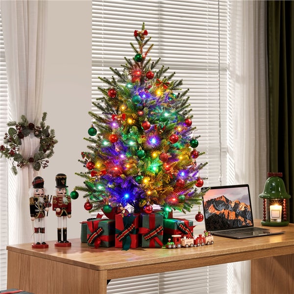 Dekorierter Weihnachtsbaum auf einem Tisch mit Laptop, Nussknackern und Geschenken