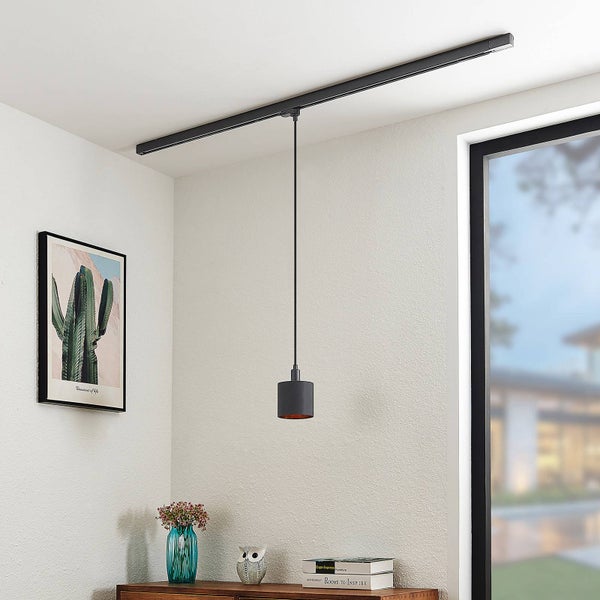 Pendelleuchte in Schwarz an einem Schienensystem an der Decke in einem hellen Zimmer über einer Kommode aus Holz.