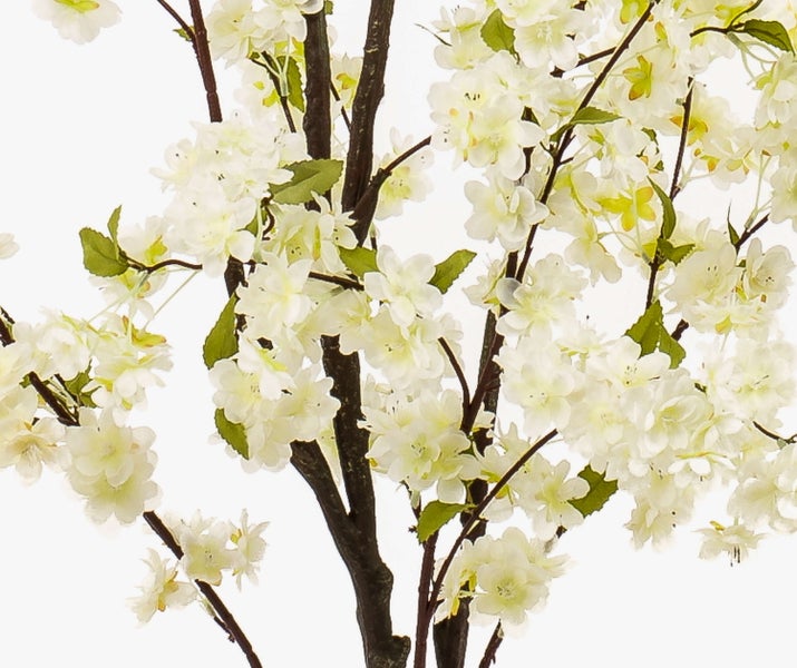 Künstlicher blühender Baum mit weißen Blüten und grünen Blättern an dunklen Zweigen.