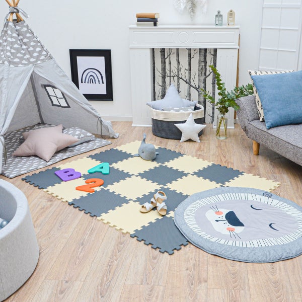 Helles Kinderzimmer mit grau-beiger Puzzlematte im Schachbrettmuster auf Holzboden, Spielzelt, grauem Sofa und Bällebad.