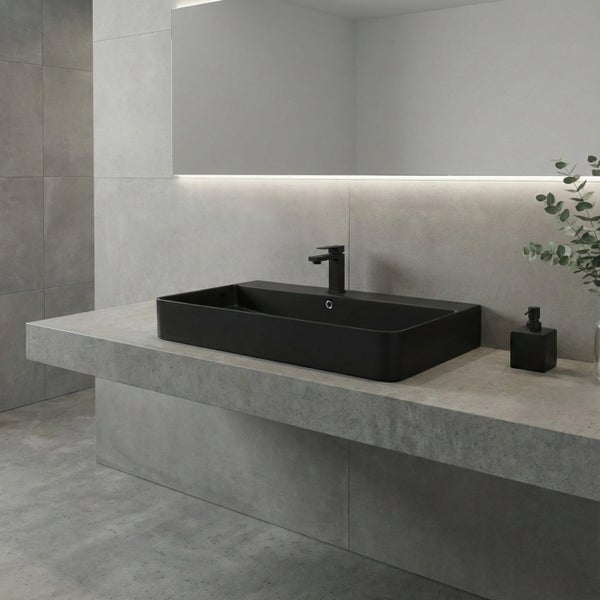 Modernes Badezimmer mit einem eckigen Aufsatzwaschbecken und einer Armatur auf einer Betonoberfläche mit großem beleuchtetem Wandspiegel.