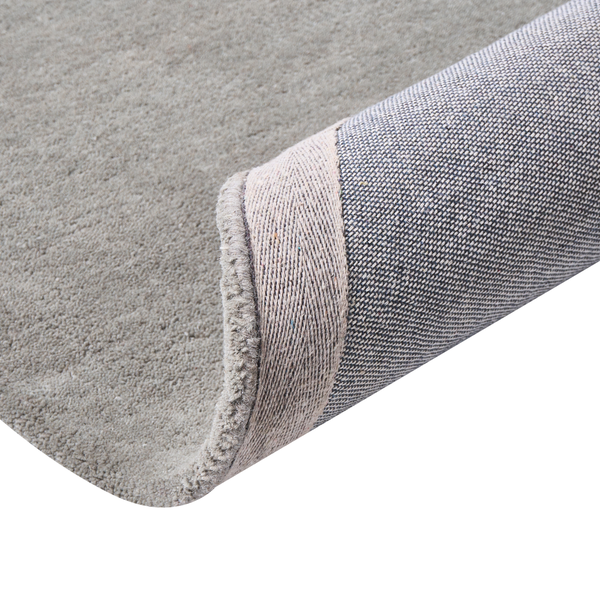 Teppich mit weichem Flor und gewebter Rückseite, eine umgeschlagene Ecke zeigt die Struktur.