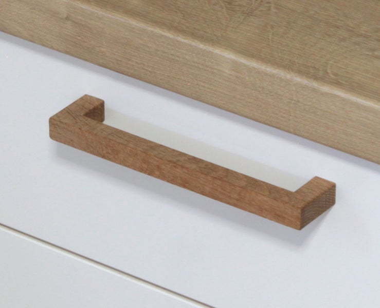 Möbelgriff aus Holz in eckigem Design, montiert an einer weißen Schubladenfront mit Holzoptik-Element.