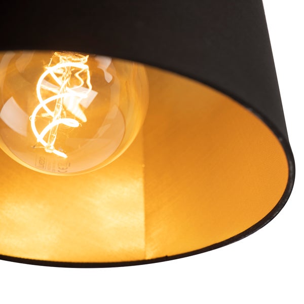 Detailansicht eines Lampenschirms mit schwarzer Außenseite und goldener Innenseite inklusive eines leuchtenden LED-Filament-Leuchtmittels.
