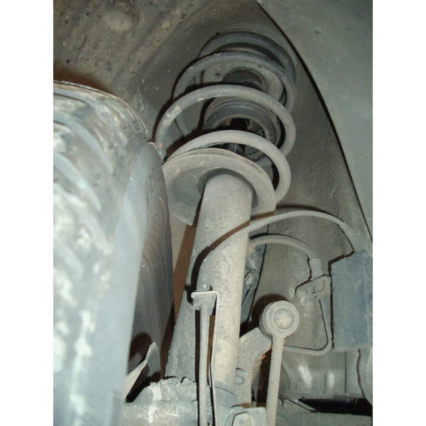 Stoßdämpfer mit Schraubfeder in der Radaufhängung eines Autos hinter einem Reifen.