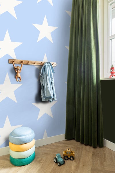 Kinderzimmer mit Sternentapete, Garderobe, Stapelhocker und Spielzeugautos.