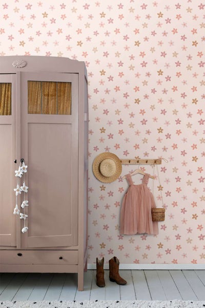 Tapete mit Blumenmuster in einem Kinderzimmer mit Kleiderschrank, Strohhut, Kinderkleid und Stiefeln vor einer floralen Wand.