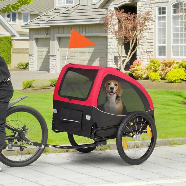 Fahrradanhänger für Hunde in Rot und Schwarz mit Sicherheitsfahne, montiert an einem Fahrrad, ein Hund sitzt im Inneren.