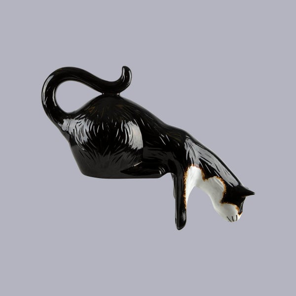 Dekofigur Katze aus glänzender Keramik in Schwarz und Weiß, kauernde Haltung für Regalkanten.