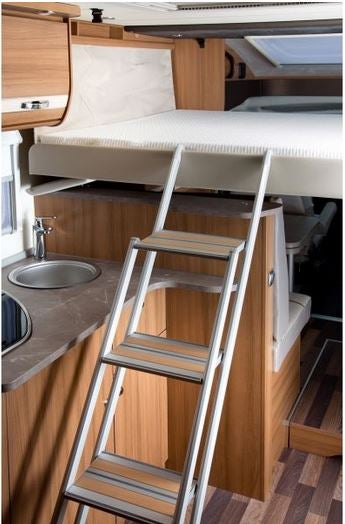Innenansicht eines Wohnmobils mit Bett und Leiter