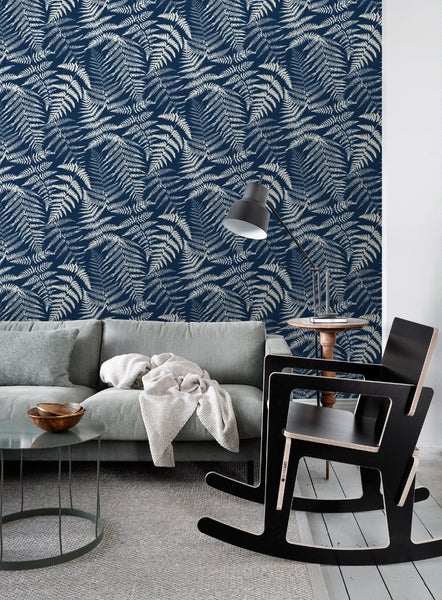 Wohnzimmer mit Sofa, Tisch, Lampe und Wandtapete mit Farnmuster