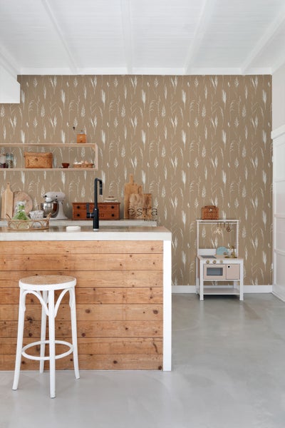 Heller Raum mit Tapete mit Gräser-Motiv, Kücheninsel aus Holz, weißem Hocker und Spielküche