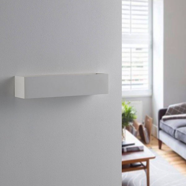 Weiße rechteckige Wandleuchte an einer strukturierten Wand in einem hellen Wohnzimmer.