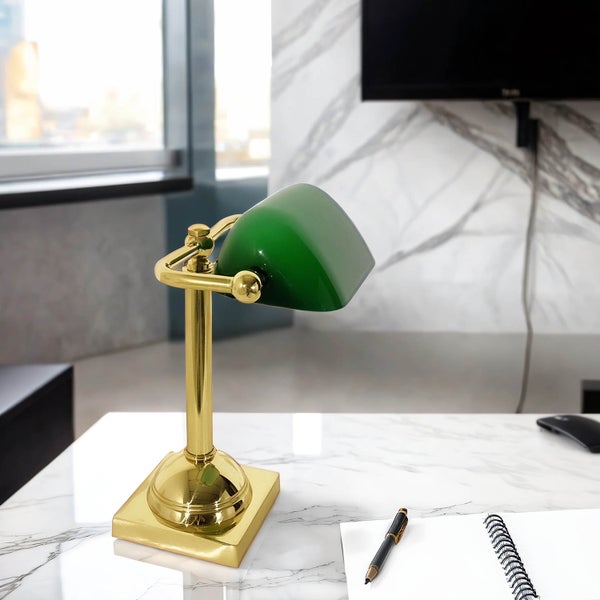 Tischleuchte mit grünem Schirm und goldfarbenem Gestell auf einem Tisch