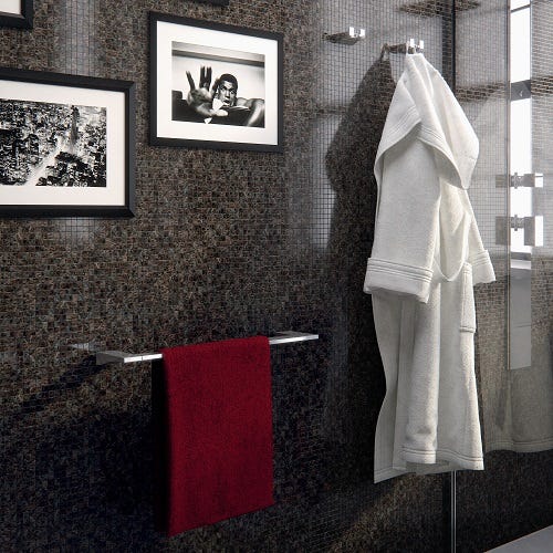 Handtuchstange aus verchromtem Metall an einer Wand mit Mosaikfliesen, mit Handtuch und Bademantel in einem modernen Badezimmer.
