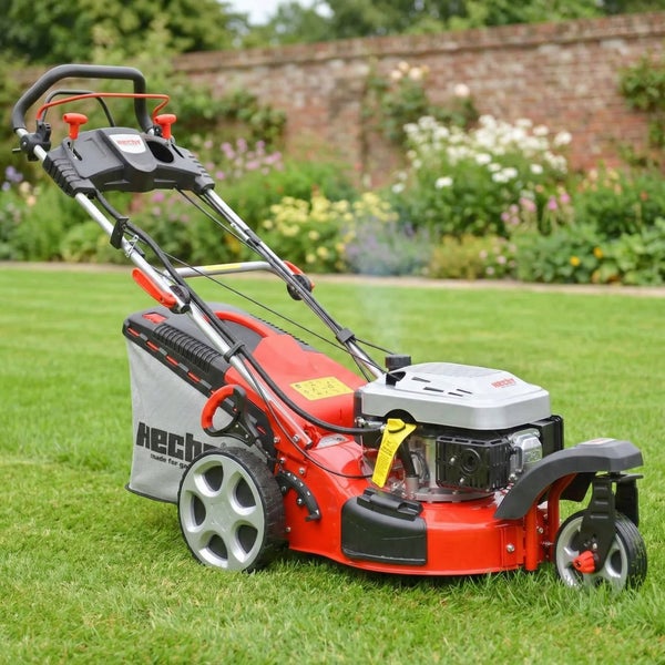 Dreirädriger Benzin-Rasenmäher von Hecht auf einer grünen Rasenfläche in einem Garten mit Fangkorb und großen Hinterrädern.