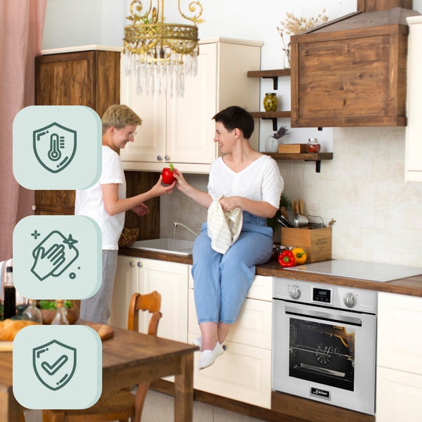 Einbaubackofen mit zwei Personen in einer wohnlichen Küche mit Holz und hellen Fronten, inklusive Symbolen für Temperaturbeständigkeit und Pflege.
