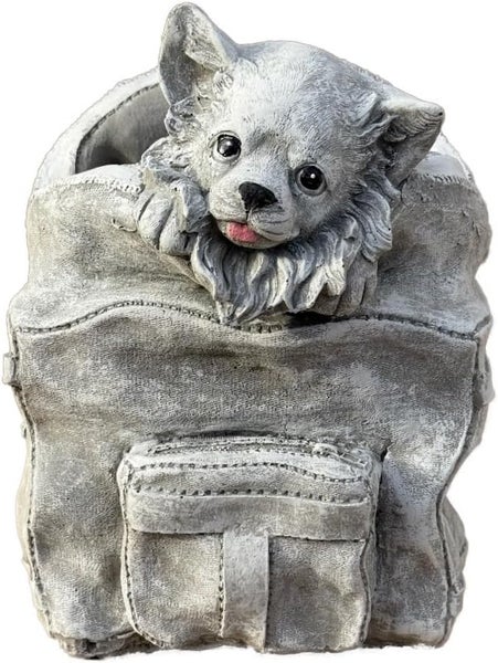 Gartenfigur aus Steinguss in Form eines kleinen Hundes, der aus einem Rucksack herausschaut.