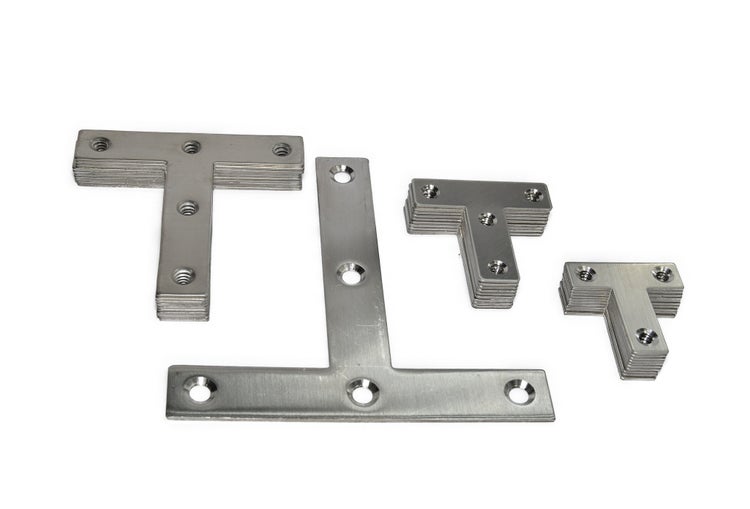 Stapel mit mehreren T-förmigen Verbindungsblechen aus Metall mit vorgebohrten Senkkopflöchern zur Holzverbindung.