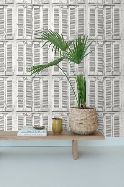 Szene mit einem Zimmer mit Tapete mit Fensterladen-Motiv, einem Holztisch und einer Zimmerpflanze