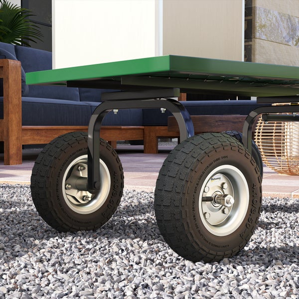 Nahaufnahme der profilierten Luftreifen eines Gartenwagens mit grünem Rahmen auf Kiesboden.
