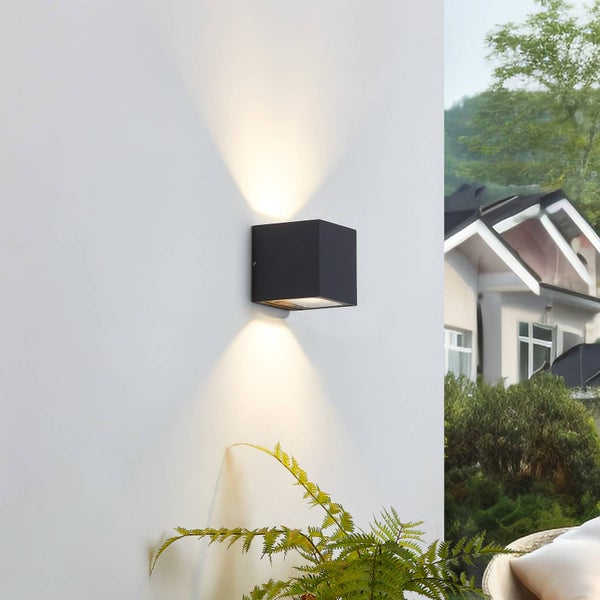 Quadratische Außenwandleuchte in Anthrazit mit Up-and-Down-Lichteffekt an einer weißen Wand.