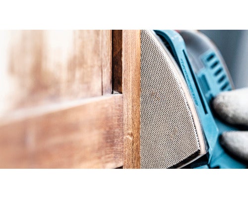 Eine Person schleift Holz mit einem Elektroschleifer.