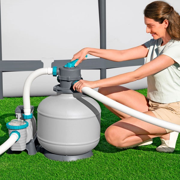 Frau bedient Sandfilteranlage für Pool auf Rasen