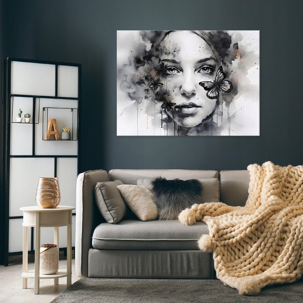 Großes Leinwandbild mit Frauenporträt und Schmetterlingen über einem grauen Sofa in einem modern eingerichteten Wohnzimmer.