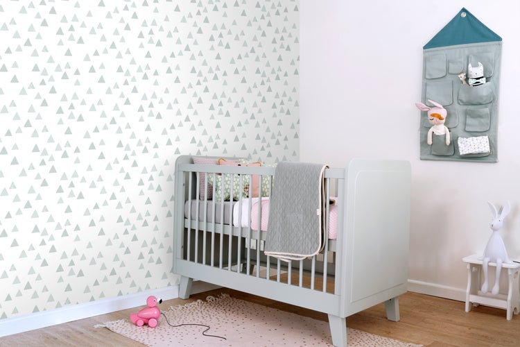 Babyzimmer mit Gitterbett, Wandtapete mit Dreiecken und Stoffaufbewahrung
