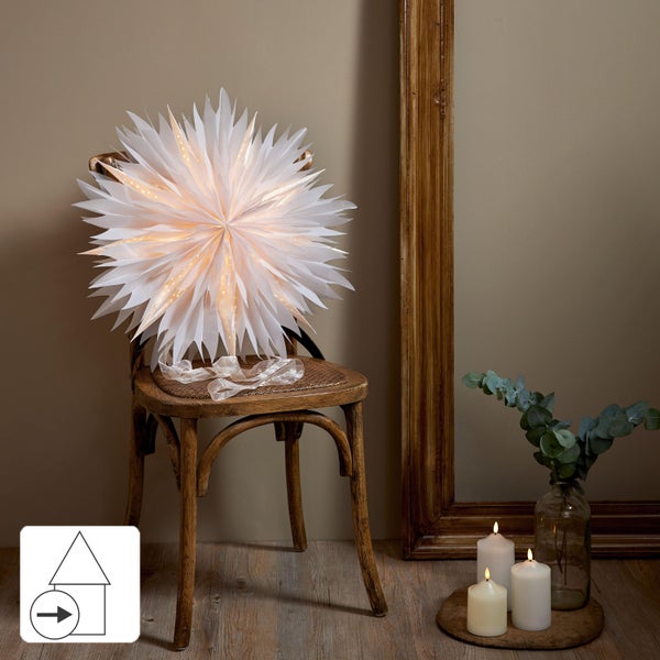 Dekorative Szene mit einem beleuchteten Papierstern auf einem Stuhl, neben Kerzen und einem Spiegel. Symbol: Energiesparend.