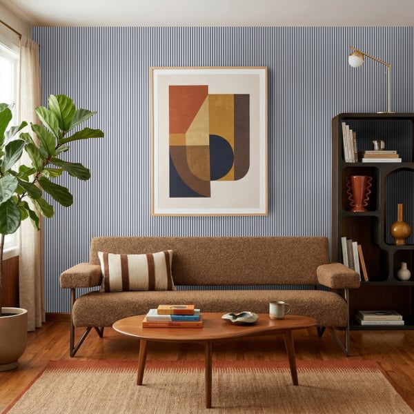 Helles, organisiertes Wohnzimmer mit blau-weiß gestreifter Tapete, braunem Sofa, Holztisch und großem abstrakten Bild an der Wand.