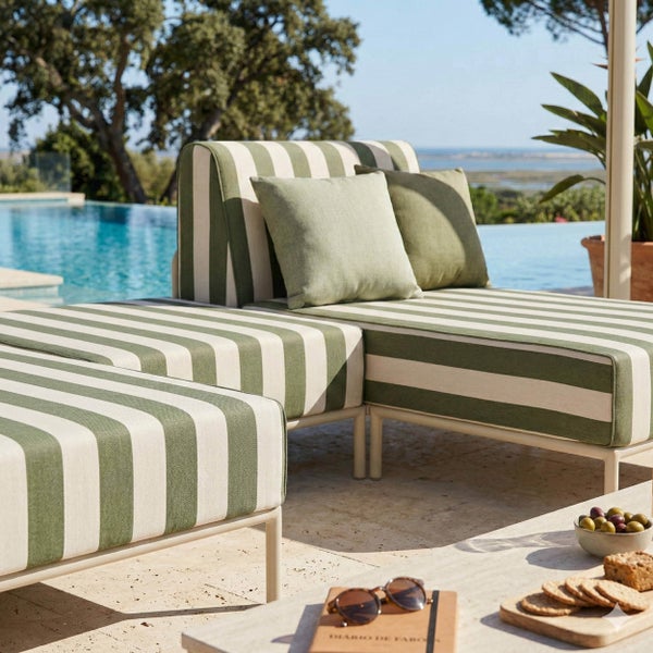 Moderne Outdoor-Lounge-Möbel mit grün-weiß gestreiften Polstern und passenden Kissen auf einer sonnigen Terrasse am Pool mit Meerblick.