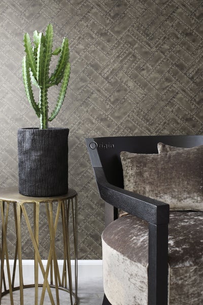 Dekorative Inneneinrichtung mit Zimmerpflanze, Beistelltisch und Sessel vor einer Wand mit Metallplatten-Tapete.