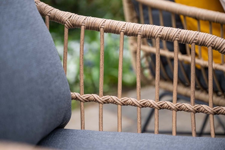 Detailansicht eines Gartenstuhls mit Geflecht in Rattan-Optik und grauem Sitzkissen.