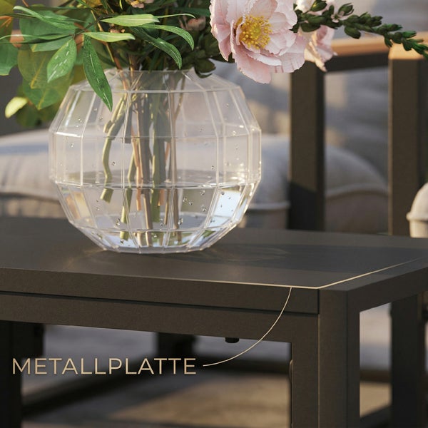 Nahaufnahme einer dunklen Metallplatte eines Garten-Loungetisches mit einer dekorativen Glasvase und Blumen.