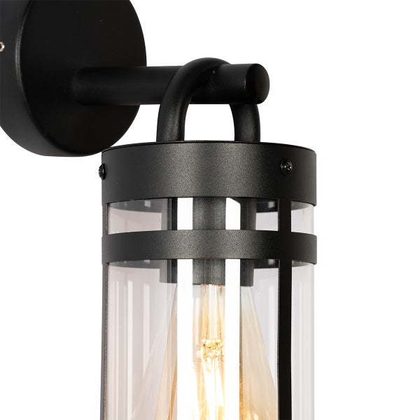 Schwarze zylindrische Außenwandleuchte aus Metall und Glas mit sichtbarem Leuchtmittel.