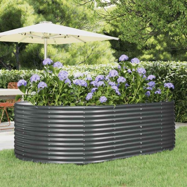 Ovales Hochbeet aus Wellblech bepflanzt mit Hortensien im Garten auf einer Rasenfläche neben einem Sonnenschirm.