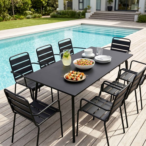 Modernes Gartenmöbel-Set aus schwarzem Metall mit großem Esstisch und acht Armlehnstühlen auf einer Holzterrasse am Pool.