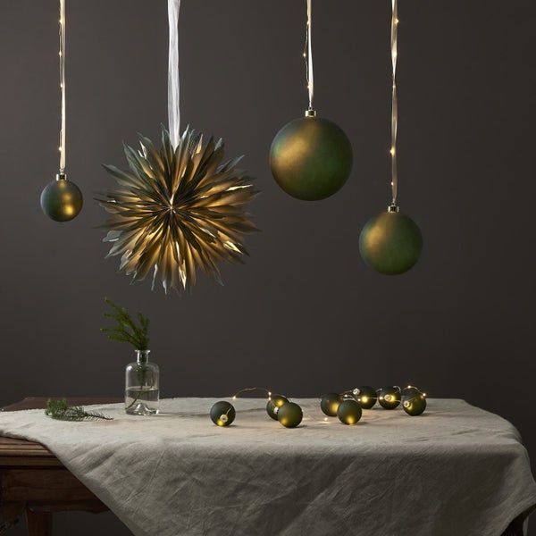 Dekorative Weihnachtsszene mit Stern, Kugeln und Lichterkette auf einem Tisch