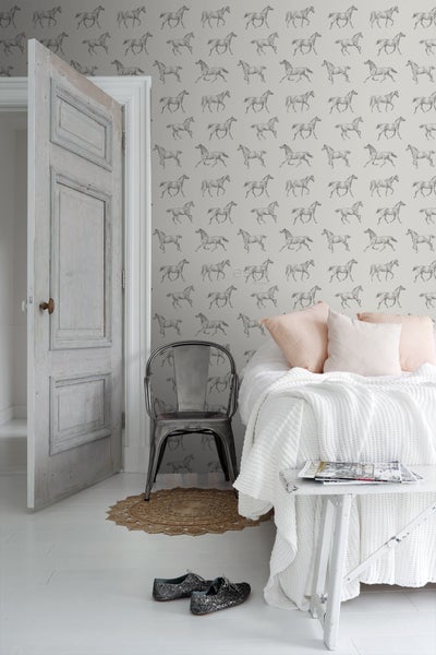 Helles Zimmer mit Bett, Stuhl, Teppich, Tapete mit Pferdemotiv und offen stehender Tür