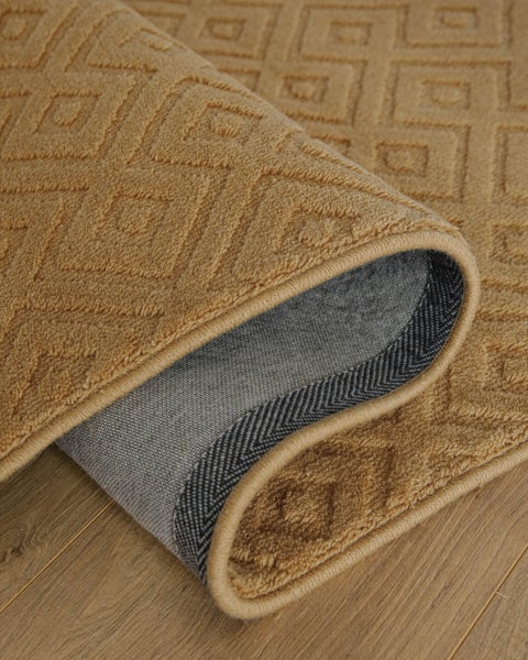 Moderner, strukturierter Teppich mit dezentem geometrischem Muster in einem hellen Wohnzimmer auf Parkettboden vor einem Sofa.