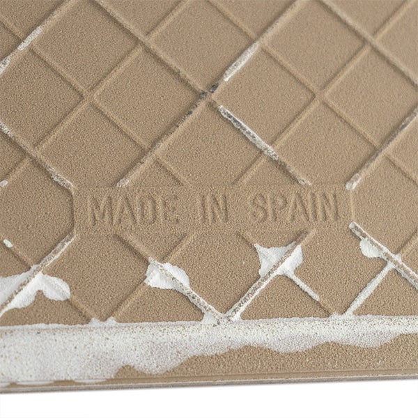 Rückseite einer Wandfliese mit eingeprägtem Herkunftshinweis Made in Spain und einem gitterförmigen Profil für besseren Halt im Fliesenkleber.